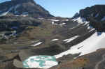 Schoolroom Glacier flows into a frozen lake surrounded by a glacial moraine.